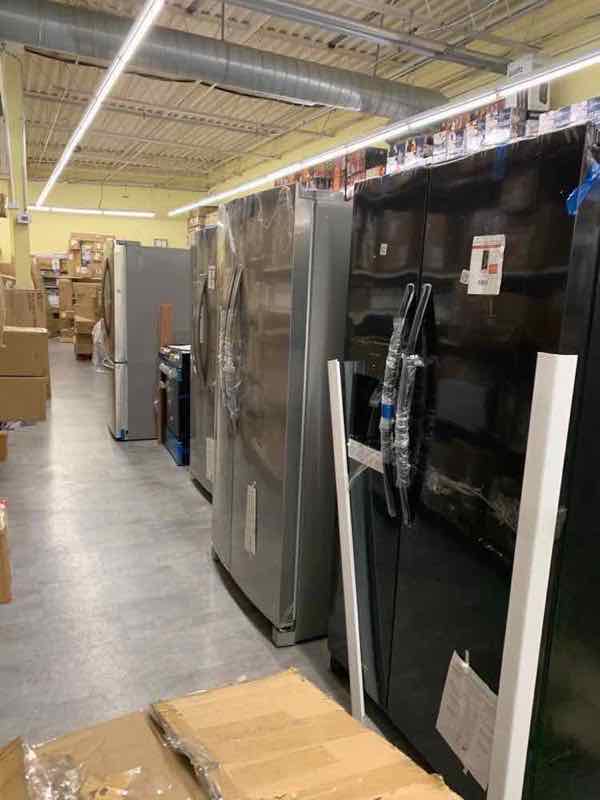 Warehouse aisle stocked with rows of major appliances ready for wholesale