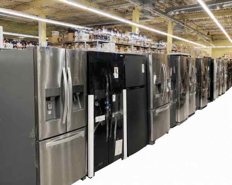 Warehouse aisle lined with stainless steel and black French-door refrigerators