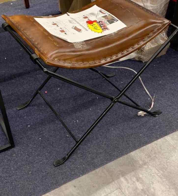 Folding leather X-frame accent stool on the floor