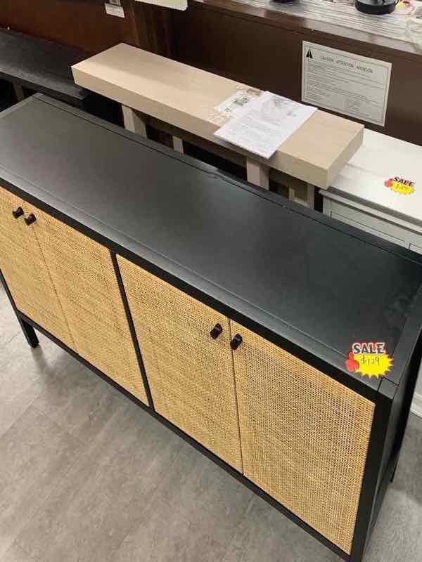 Black storage sideboard cabinet with natural rattan cane doors on the store floor